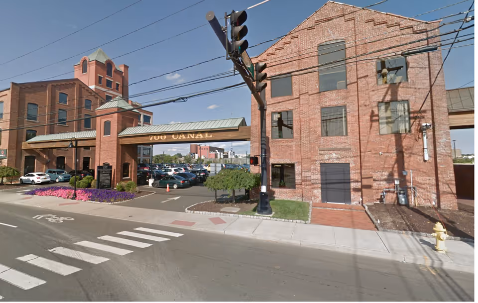 Exterior view of a brick senior living facility entrance at a street corner.