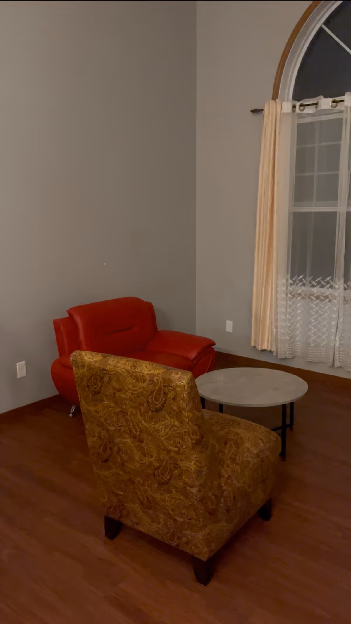 Cozy living room with a red armchair, patterned chair, and round coffee table.