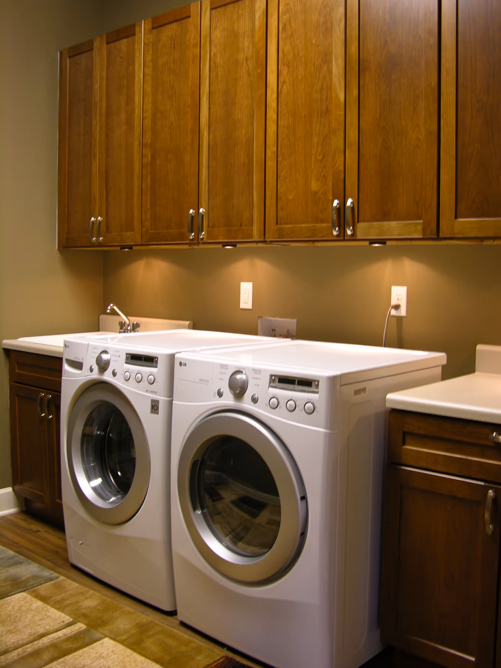 Laundry room with front-loading washers and wooden upper cabinets.