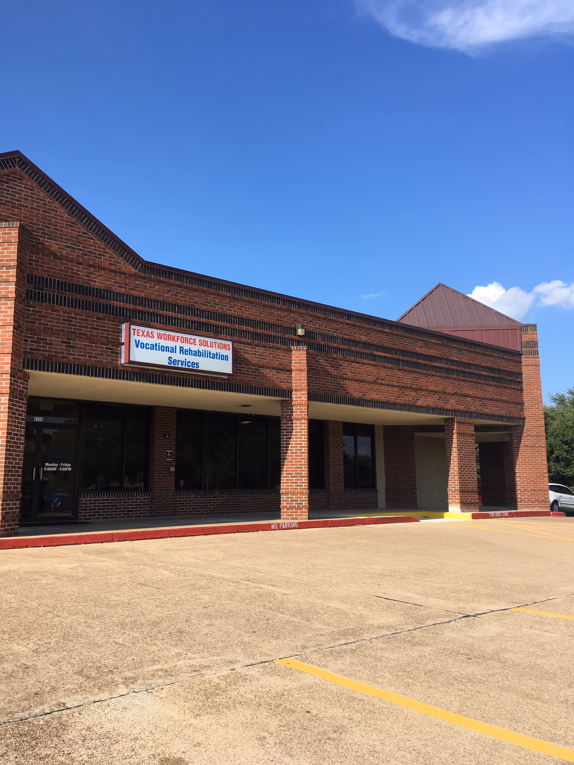 Brick building exterior with a Texas Workforce Solutions sign and empty parking lot.