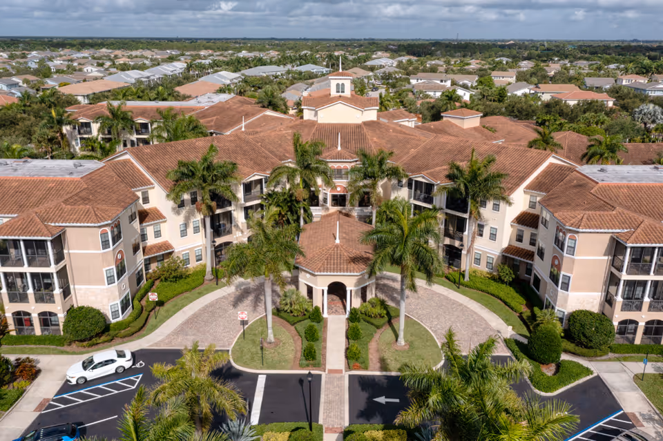 Aerial view of Addington Place of Jupiter's front exterior with palm trees and circular driveway.