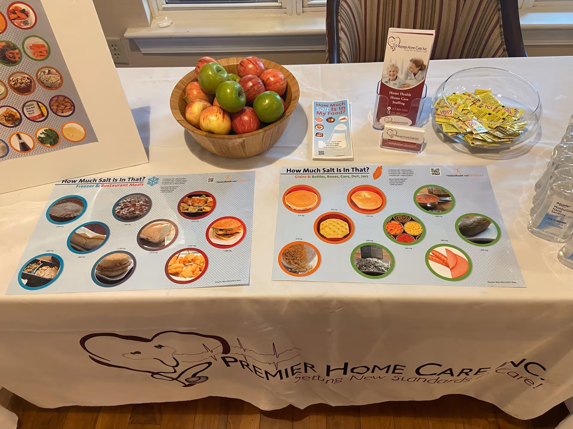 Table set with fruit bowl, brochures, and Premier Home Care branding in an indoor facility.
