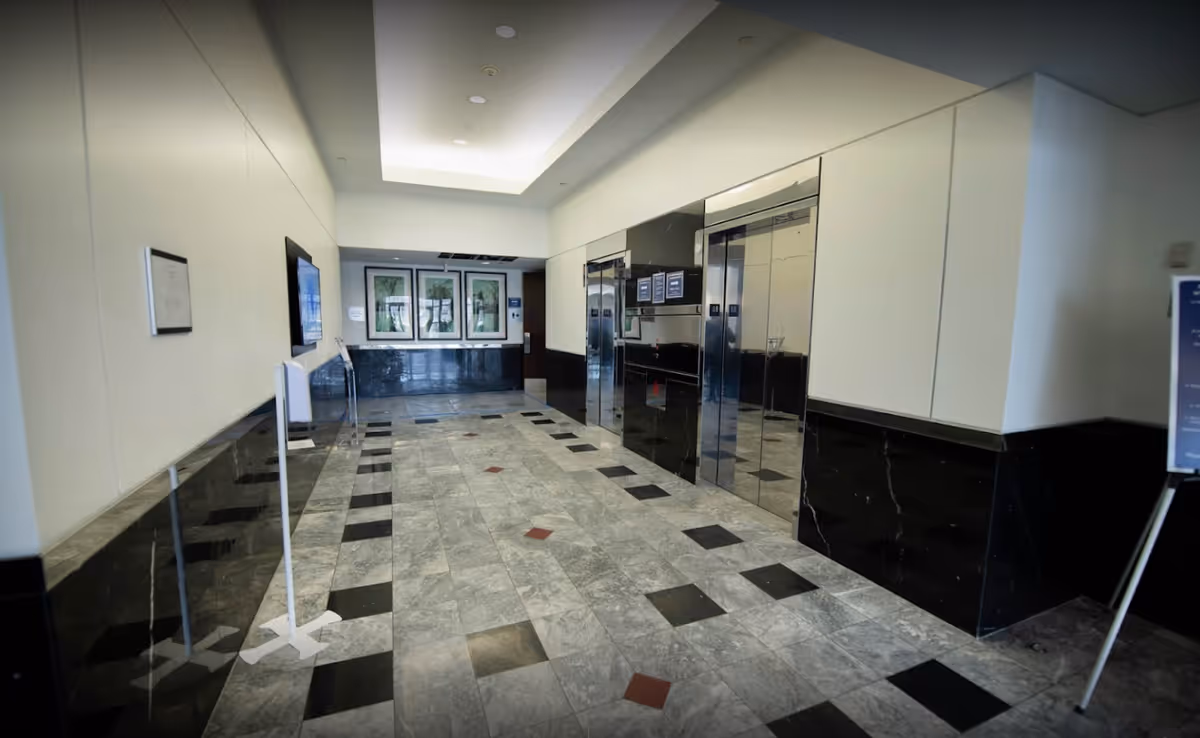 Modern hotel-like lobby with elevators and art along a marble-tiled hallway.