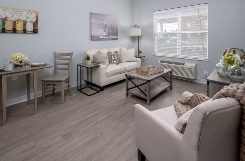 Cozy furnished living room in a senior facility with sofa, chair, and coffee table.