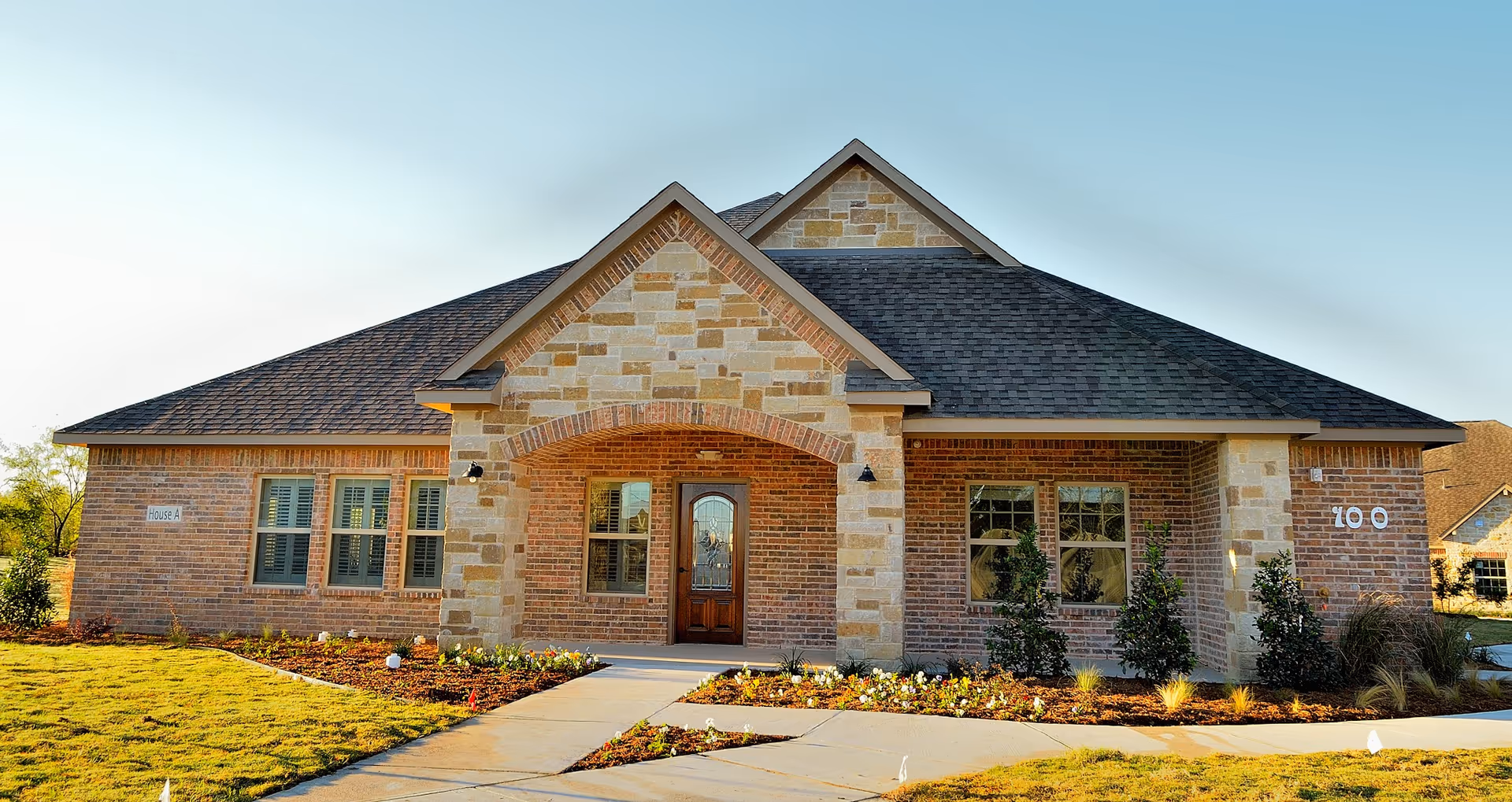 Brick senior living facility with stone accents, arched entrance, and manicured landscaping.