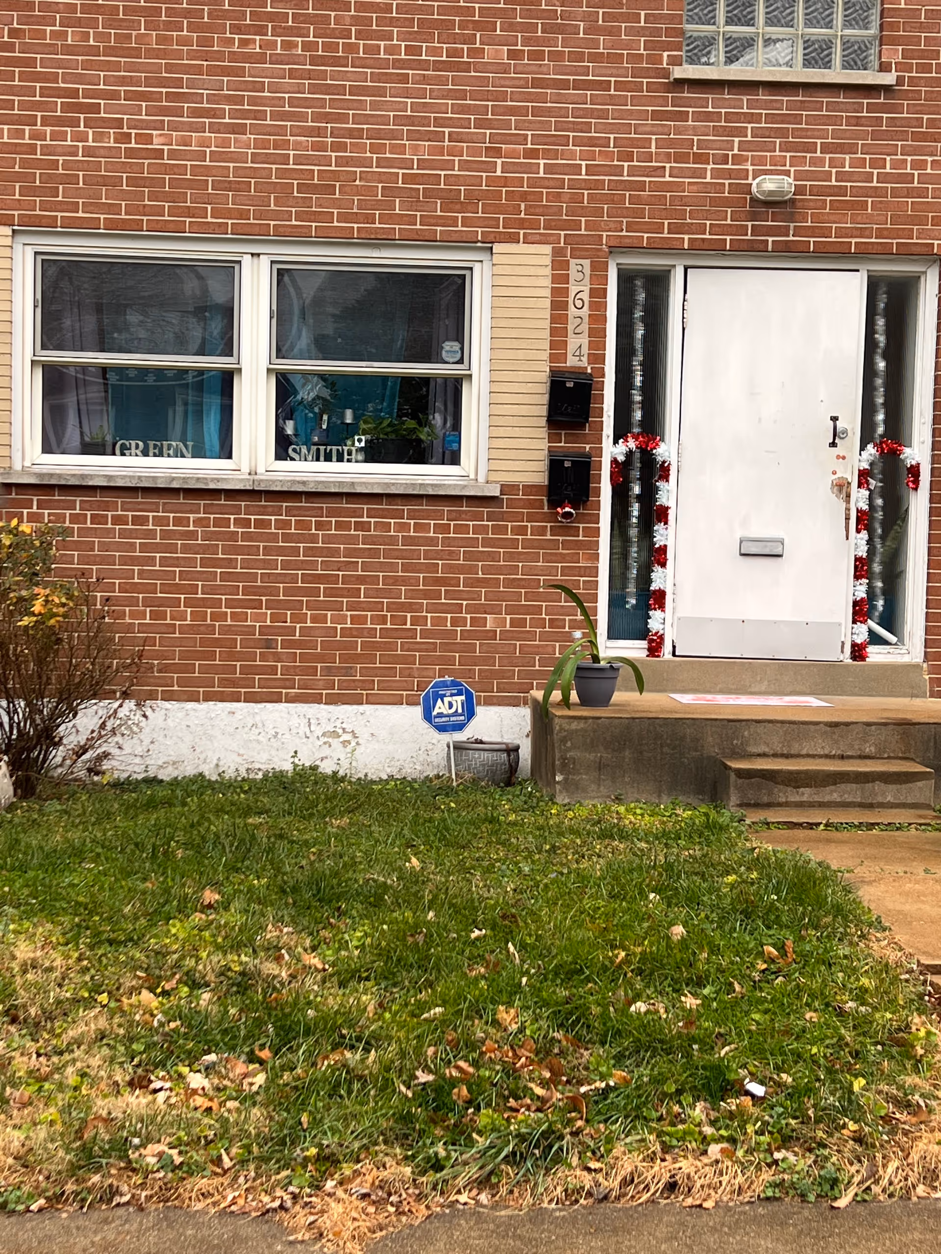 Brick building entrance for GreenSmith Care Services with white door and garland decorations.