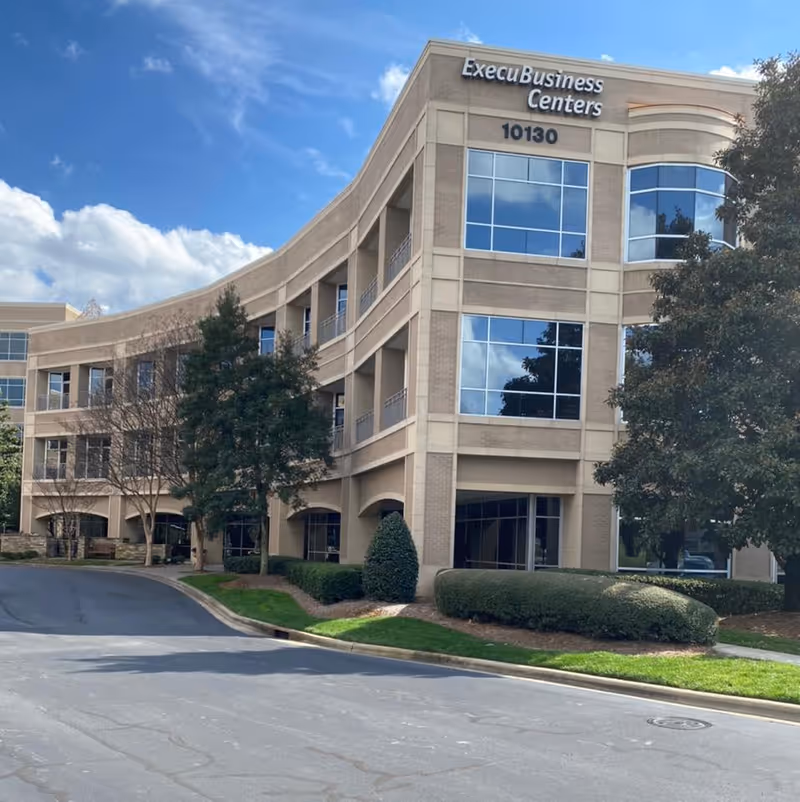 Exterior view of a curved tan-brick building labeled ExecuBusiness Centers.