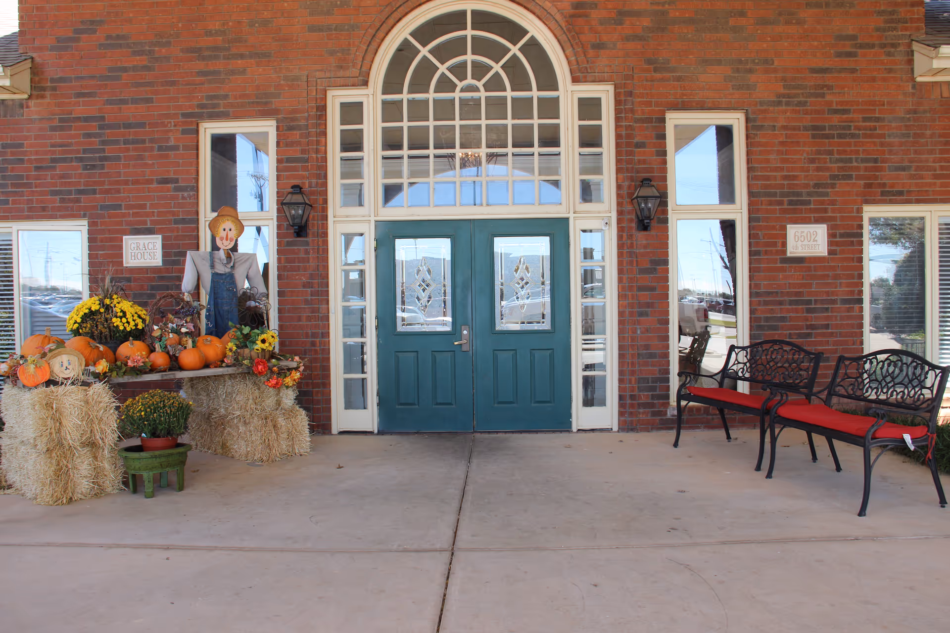 Exterior brick entrance at Wilshire on 4th with teal doors and pumpkins