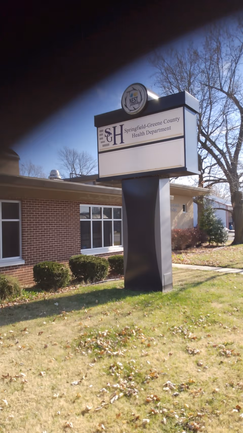 Outdoor sign on a brick building displaying Springfield-Greene County Health Department with a logo.