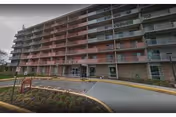 A multi-story senior living building with balconies and a curved driveway.