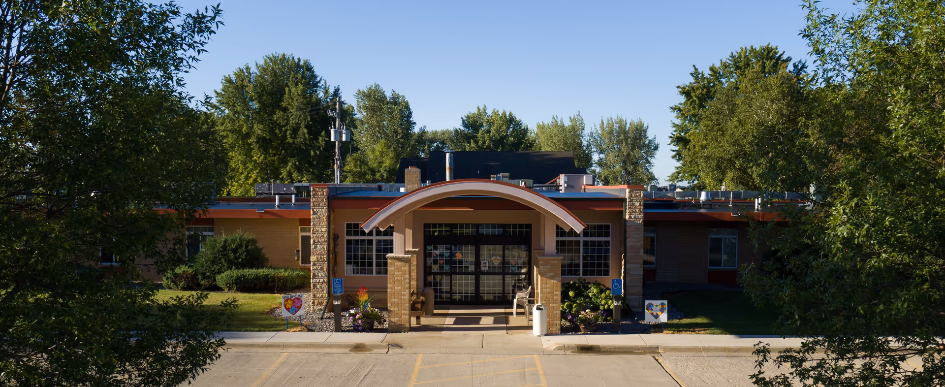 Front view of Renvilla Health Center entrance with curved canopy and surrounding trees.