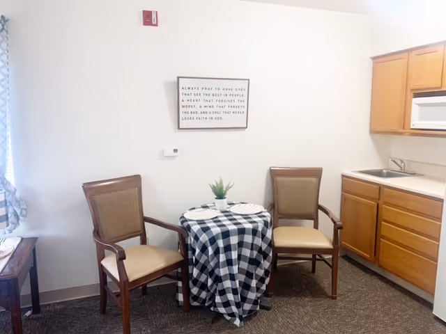 Two chairs surround a checkered table with a small plant in a cozy dining area.