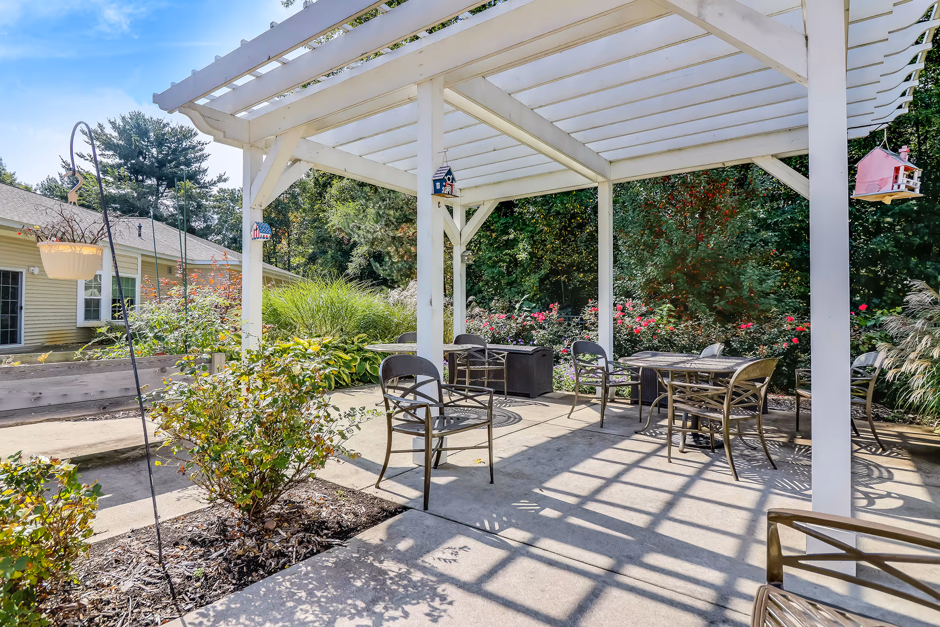 Outdoor patio with seating under a white pergola at Maple Lake Assisted Living.