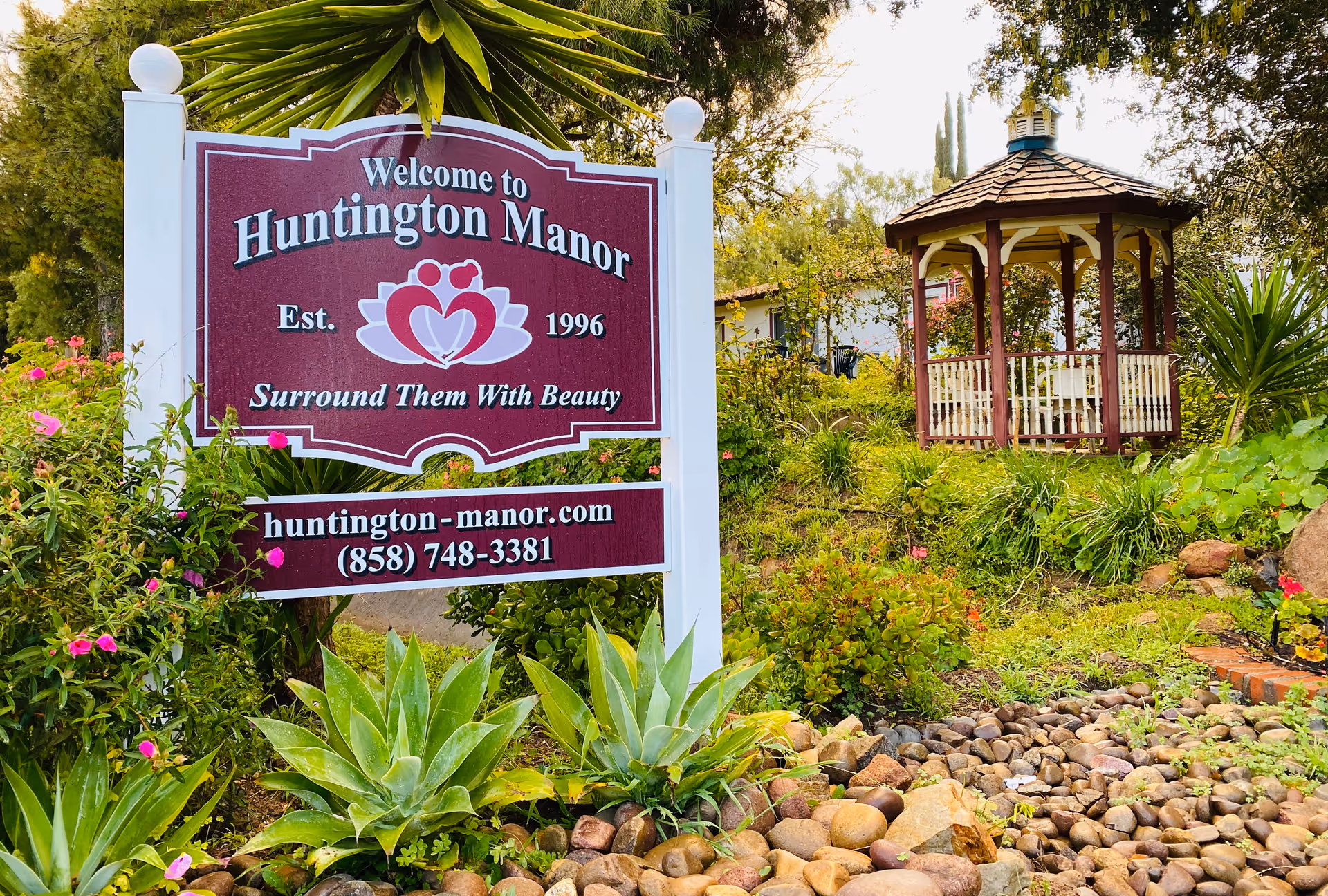 Sign welcomes visitors to Huntington Manor with landscaped grounds and a gazebo.