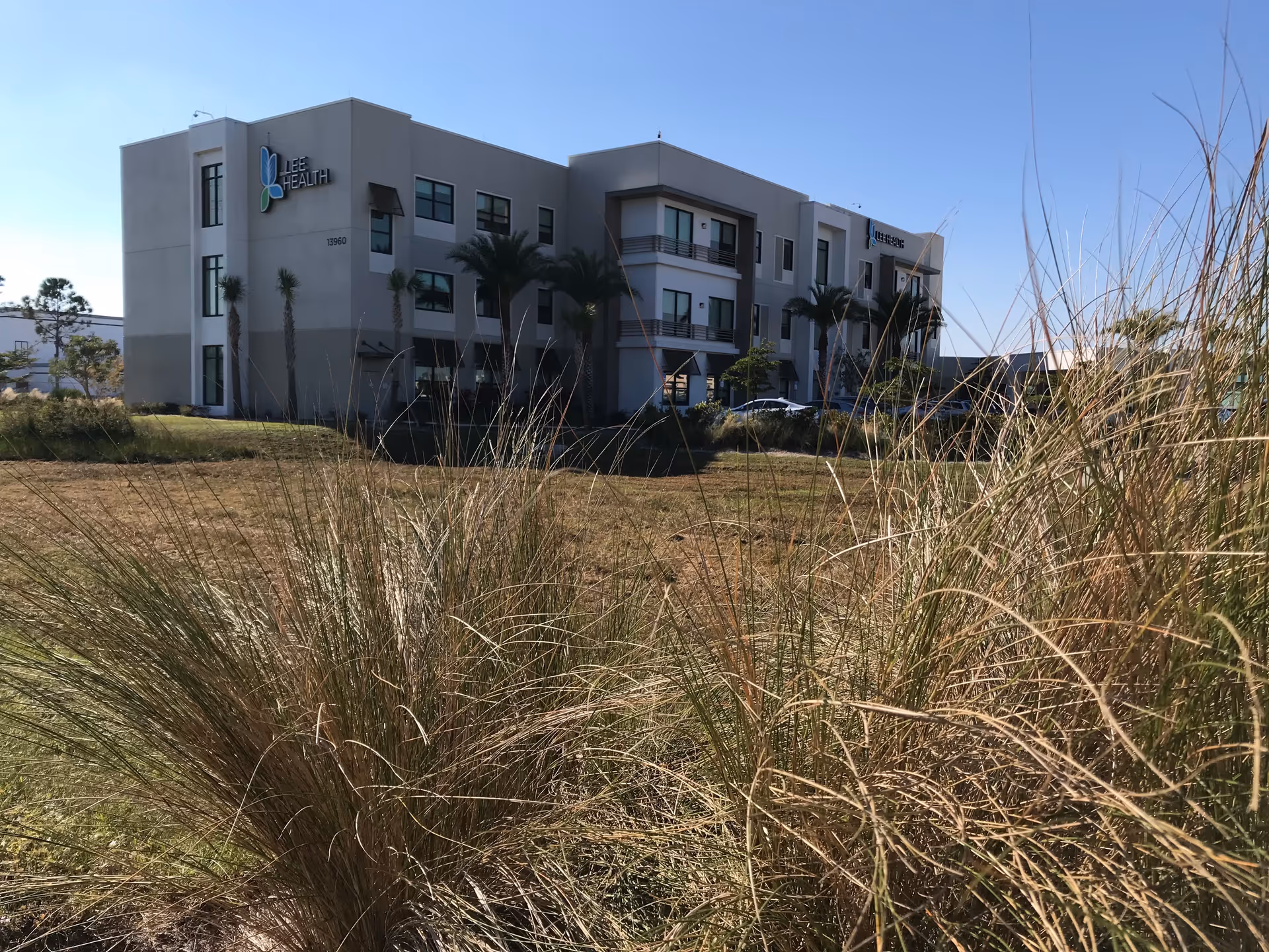 Exterior view of a modern, multi-story skilled nursing facility with palm trees.