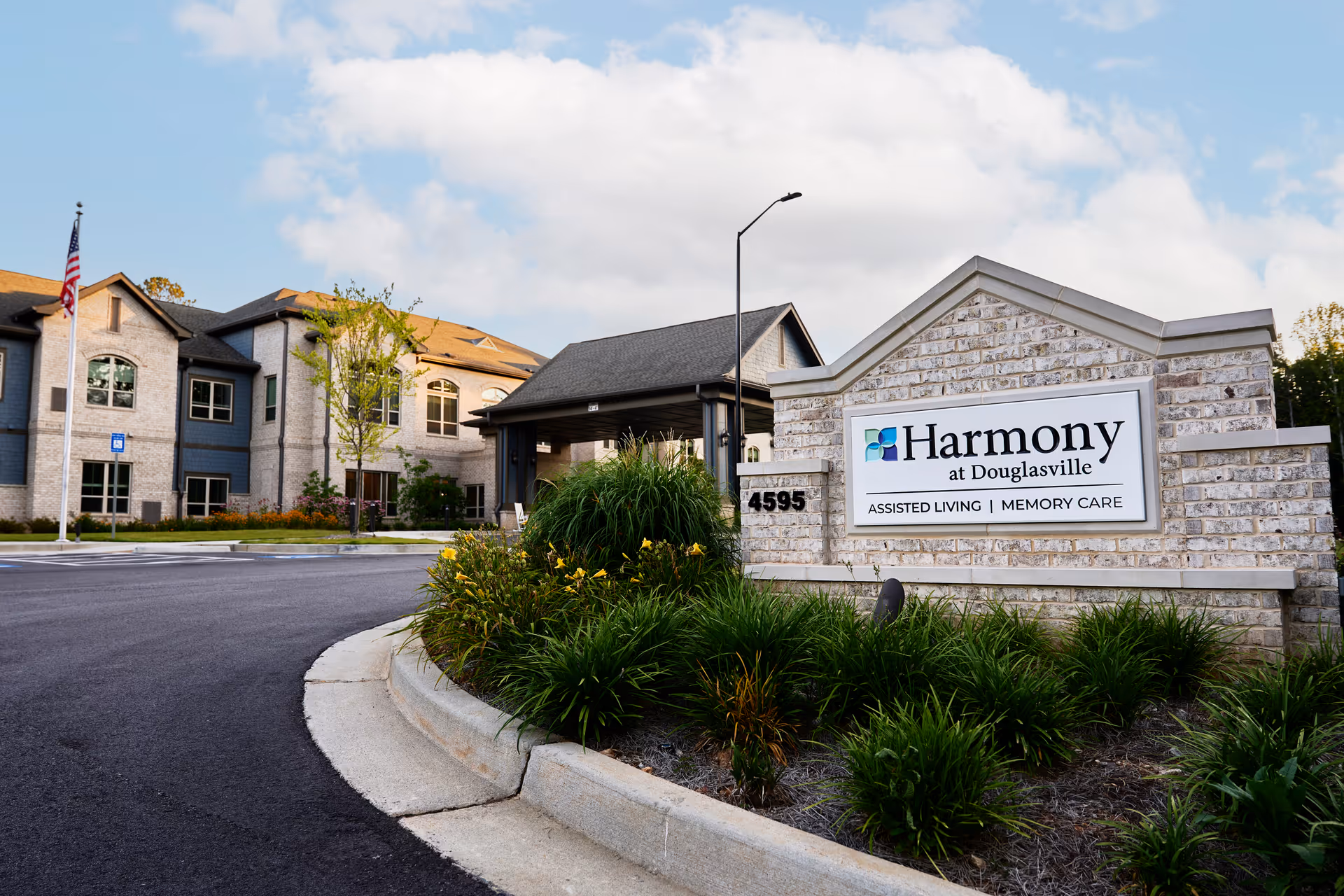 Exterior view of Harmony at Douglasville facility with sign, landscaping, and entrance drive.