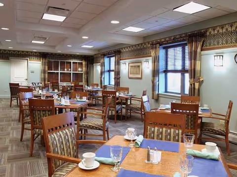 A spacious senior dining room with multiple tables set with place settings.