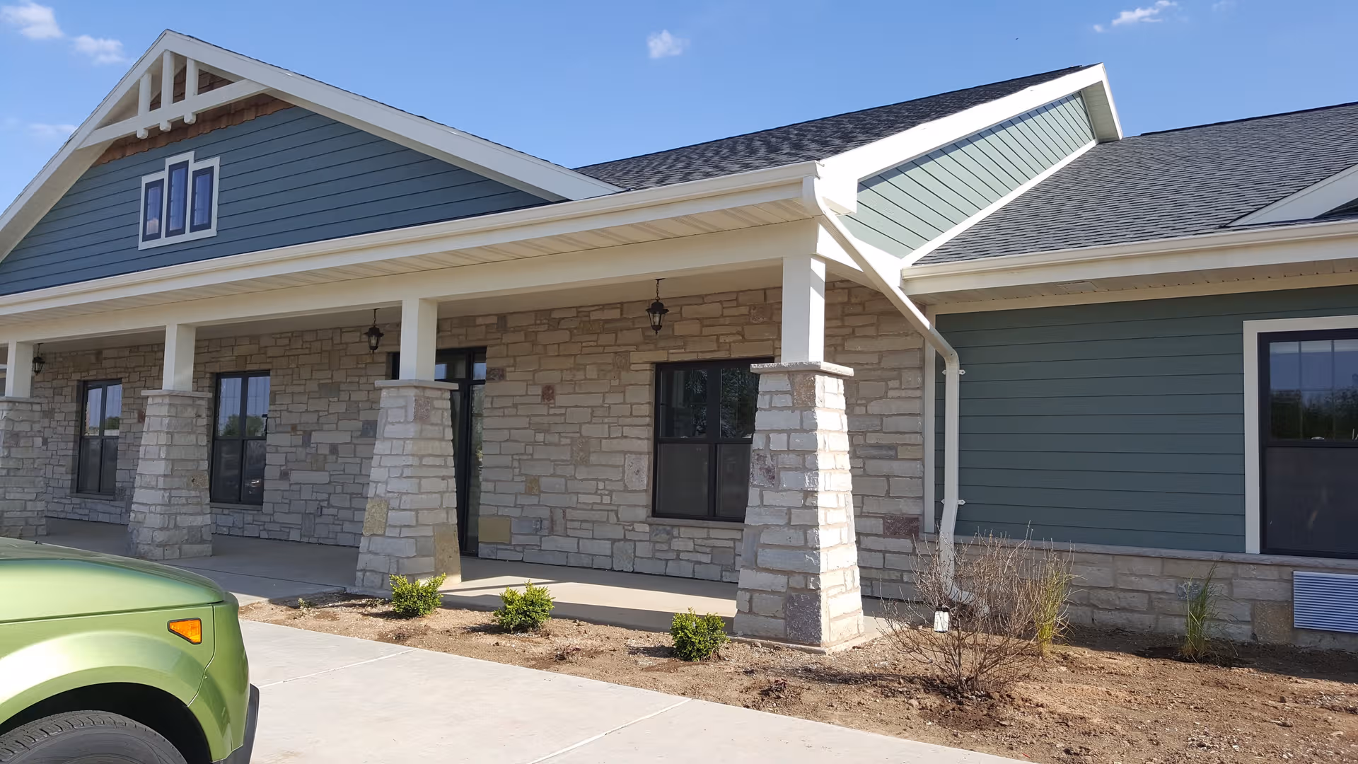 Exterior view of Country Villa Assisted Living Pulaski showing stone pillars and green siding.