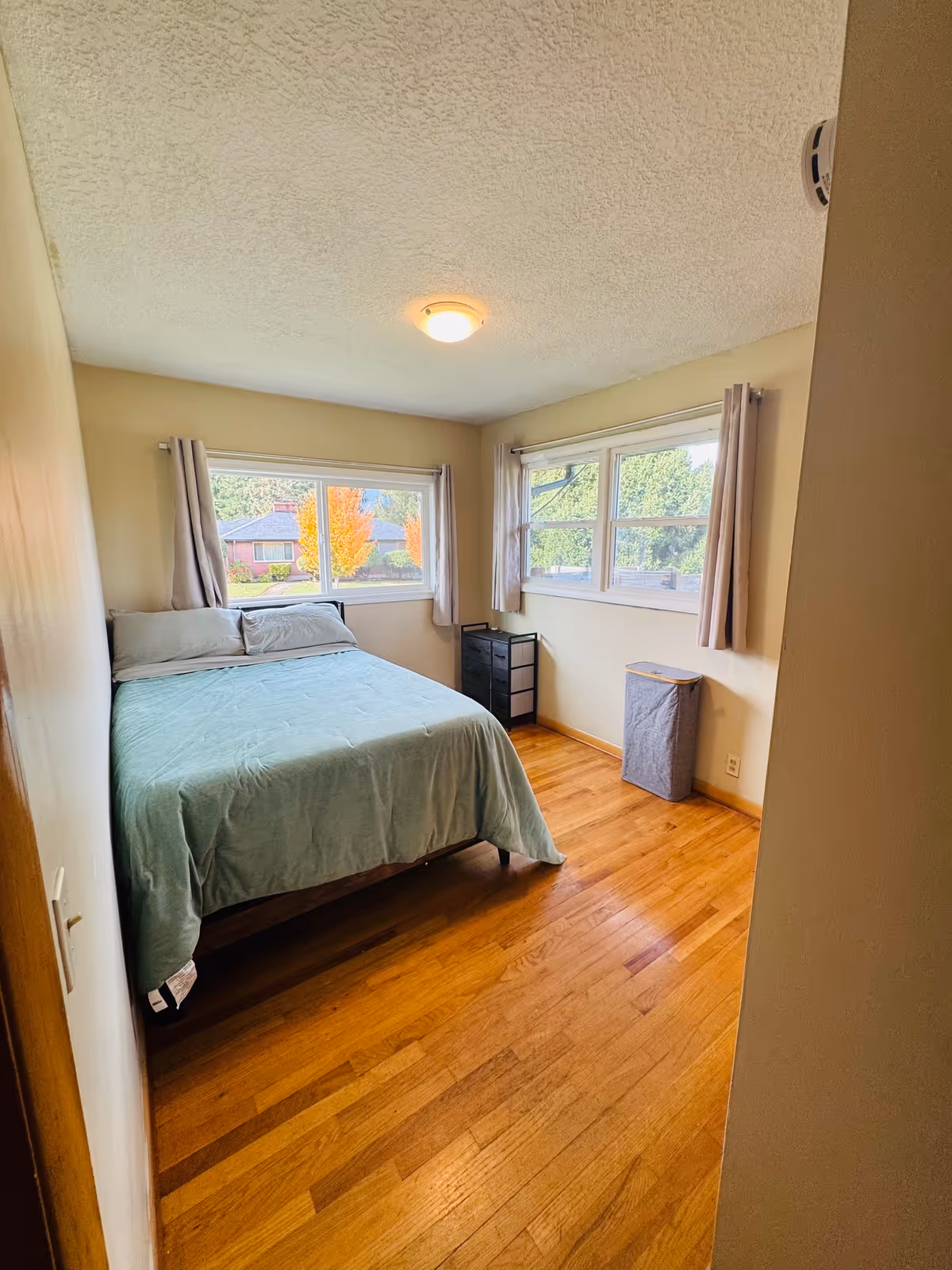 Small bedroom with a bed, windows, and minimal furniture.
