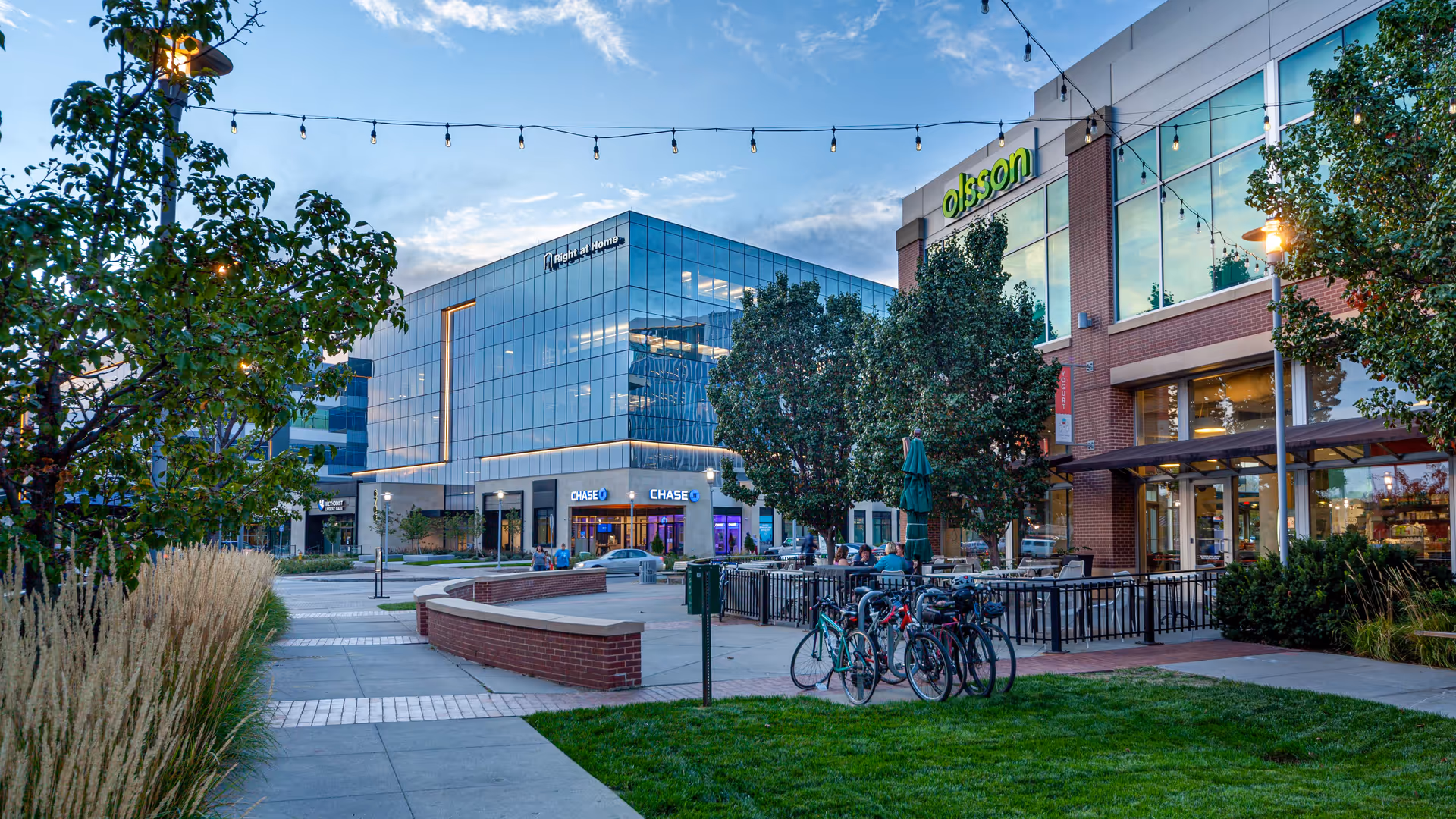 Outdoor plaza in front of Right At Home Corporate Headquarters with glass building and bikes.