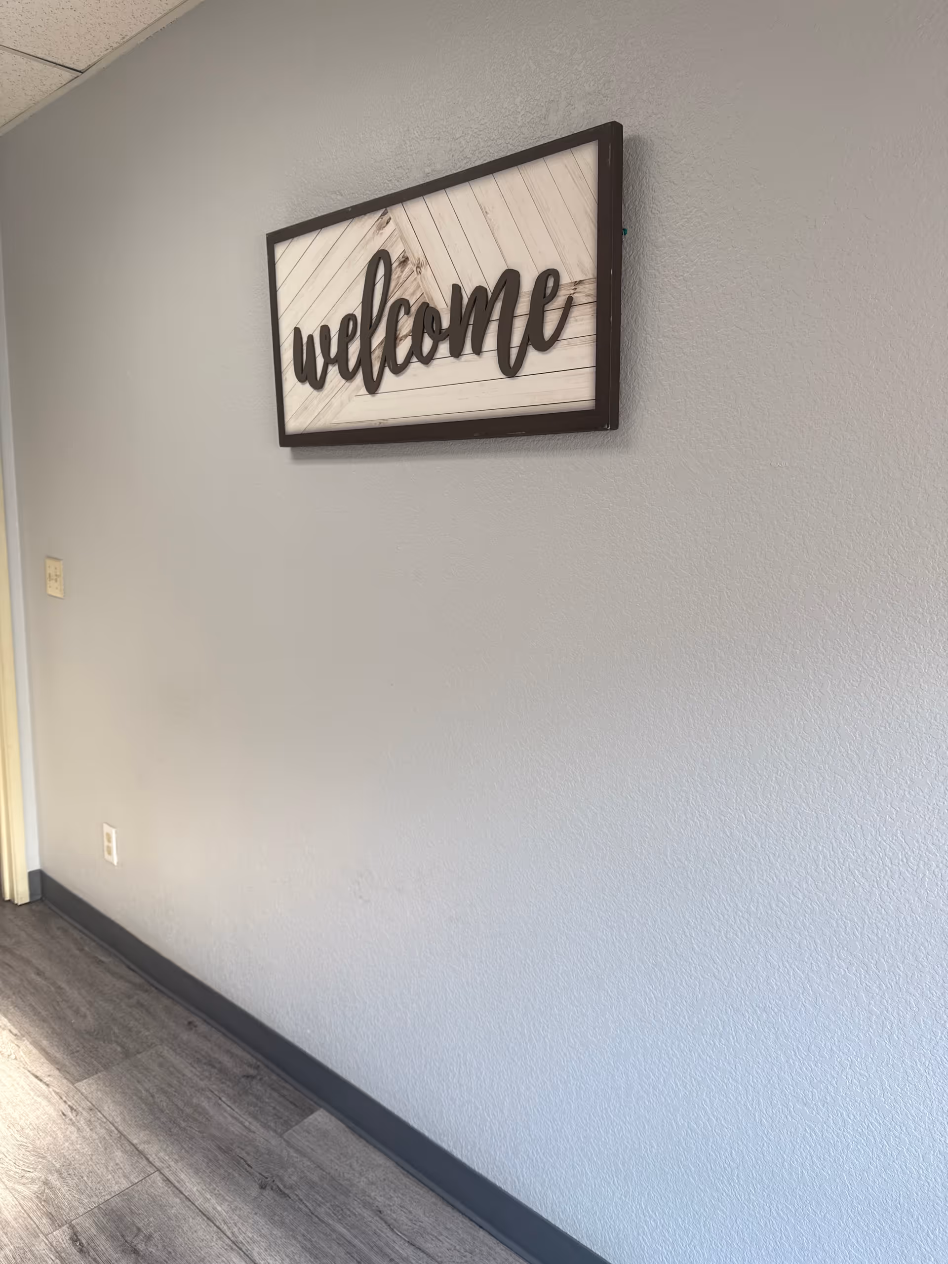 Interior hallway wall with a framed 'welcome' sign.