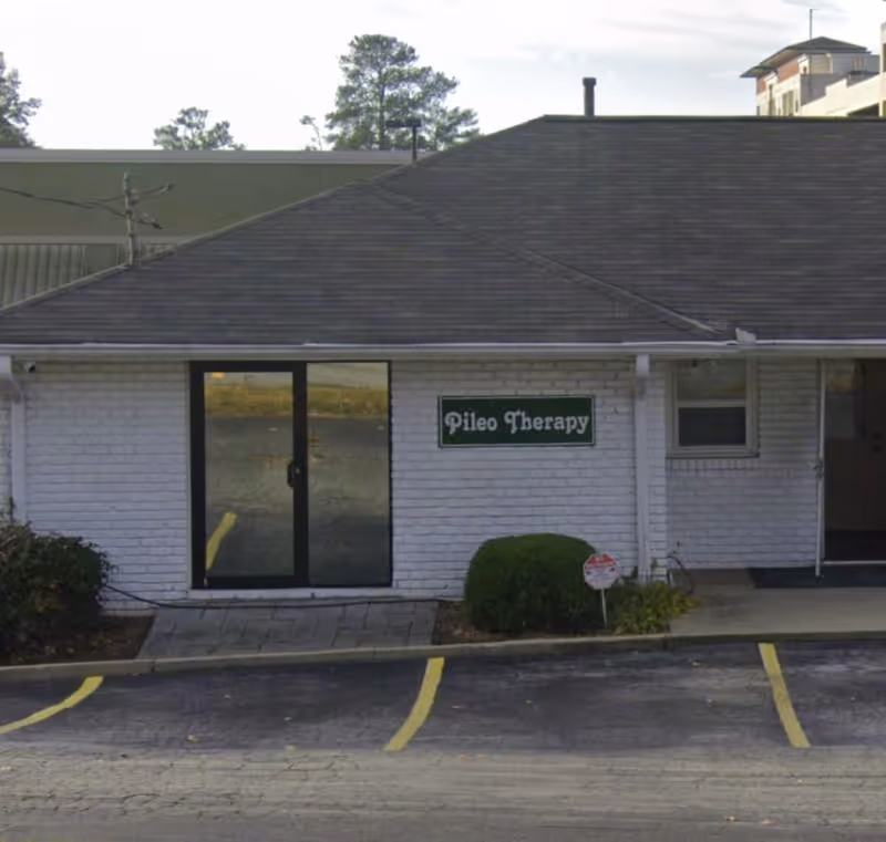 Exterior view of a single-story brick facility with a green sign.