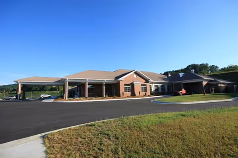 Exterior of a single-story brick senior living facility with parking lot.