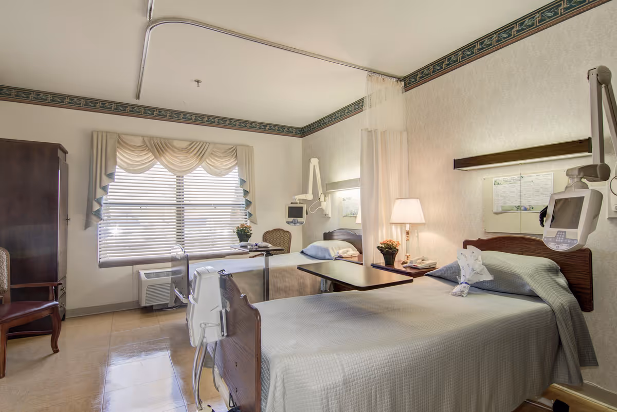 A hospital-style patient room with two beds, medical equipment, curtains, and soft lighting.