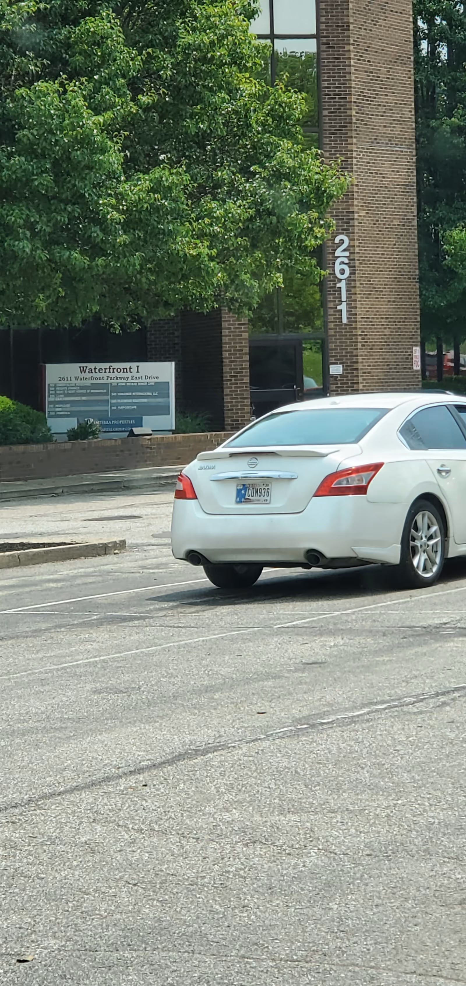 Exterior of a brick building with a white car parked in the front lot.