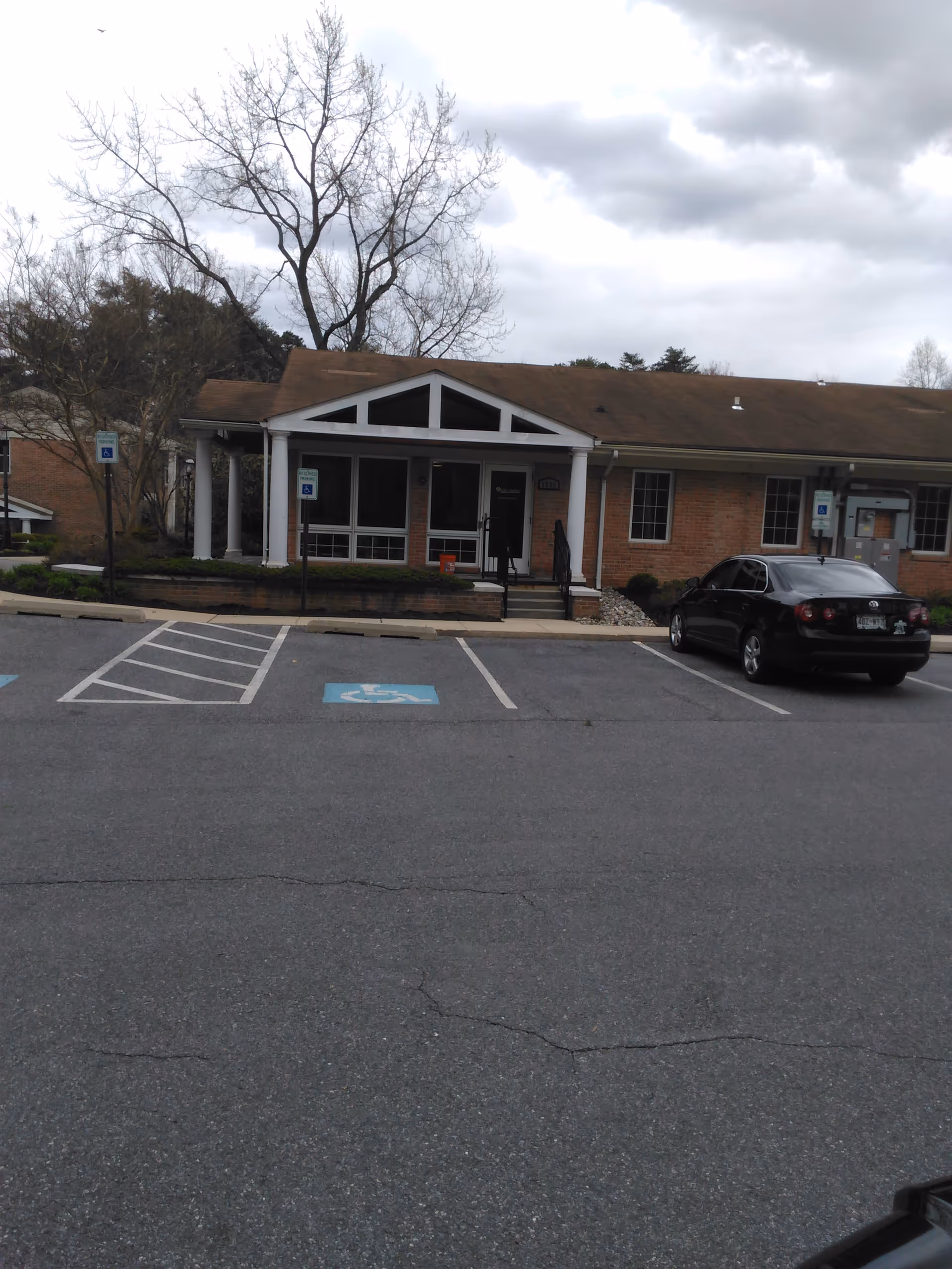 Exterior view of Bello Machre senior living facility entrance with parking lot.