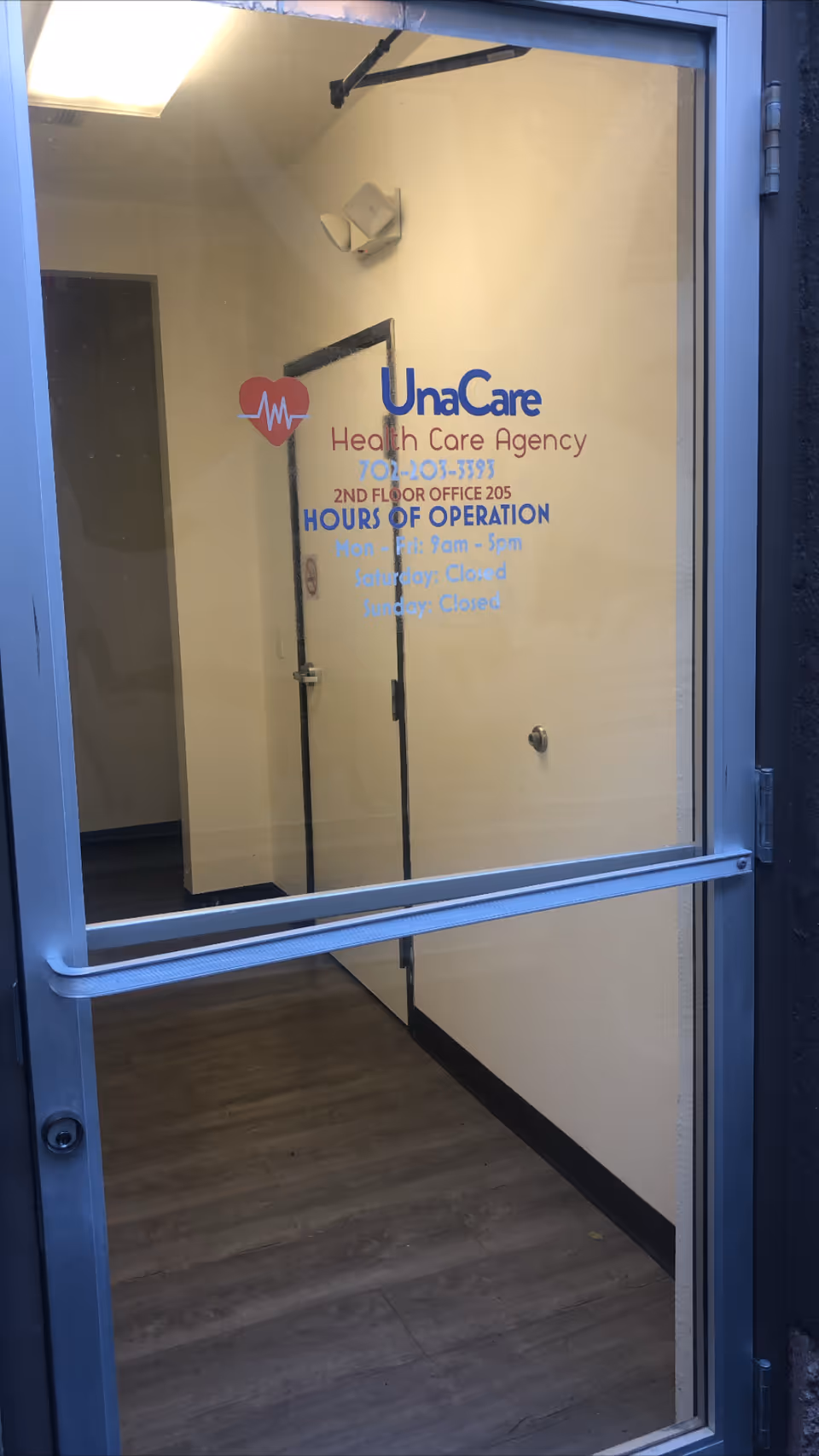 Glass door entrance displays UnaCare Health Care Agency logo with hours inside a hallway.