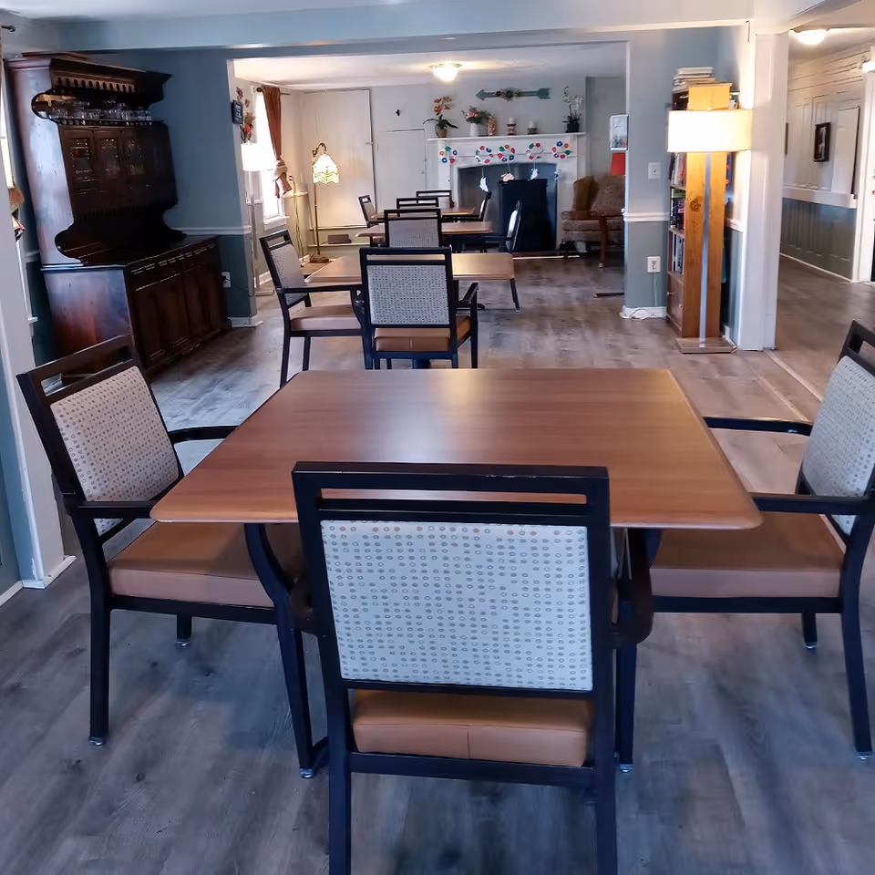 Senior living dining room with several tables and upholstered chairs in a bright interior.