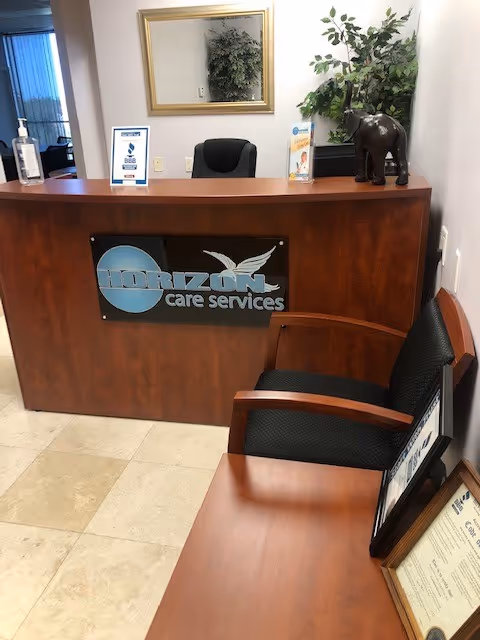 Reception desk with Horizon Care Services sign, chairs, plants, and brochures in a lobby.