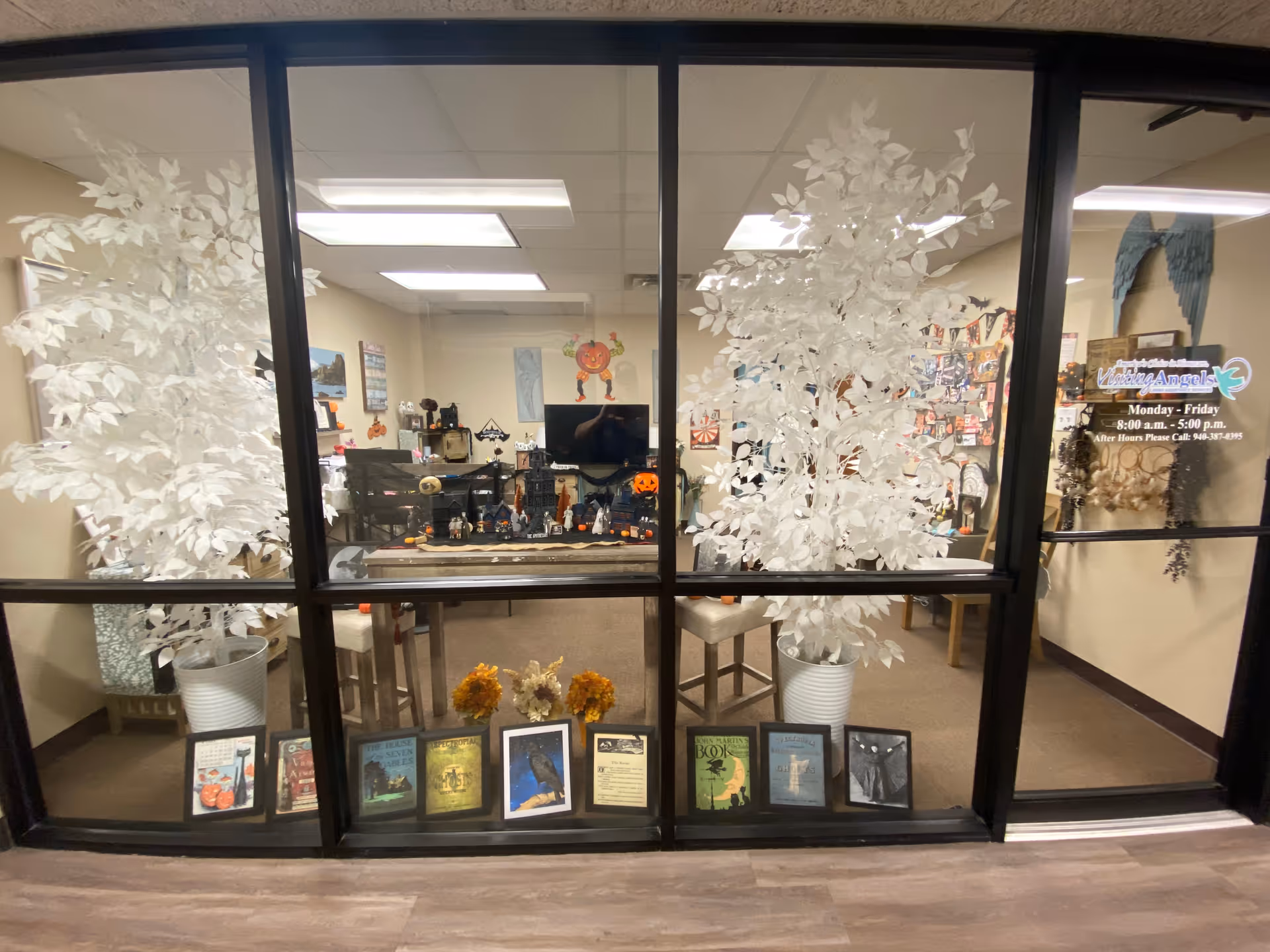 Interior office space visible through glass walls with frosted trees and decorative displays.