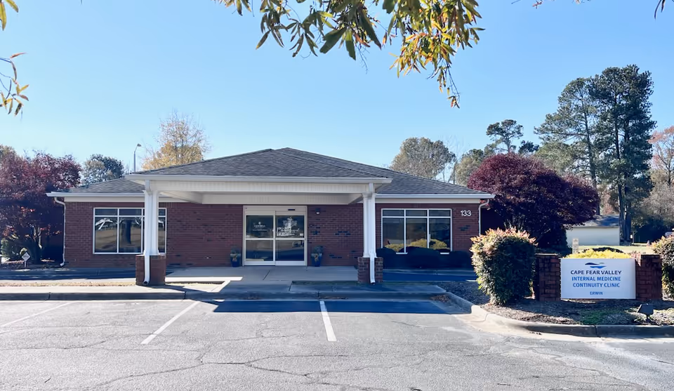 Front view of a brick clinic building with a covered entrance and parking