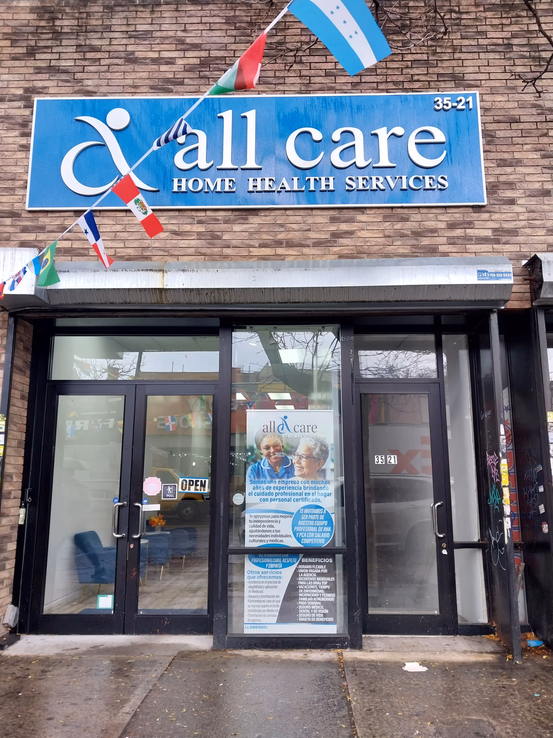 Blue sign reading All Care Home Health Services above glass entrance doors of a brick building.