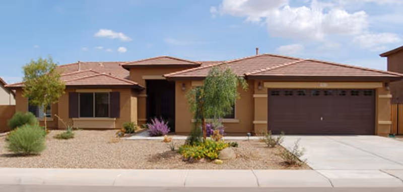 Front exterior of a single-story tan assisted living home with a two-car garage.