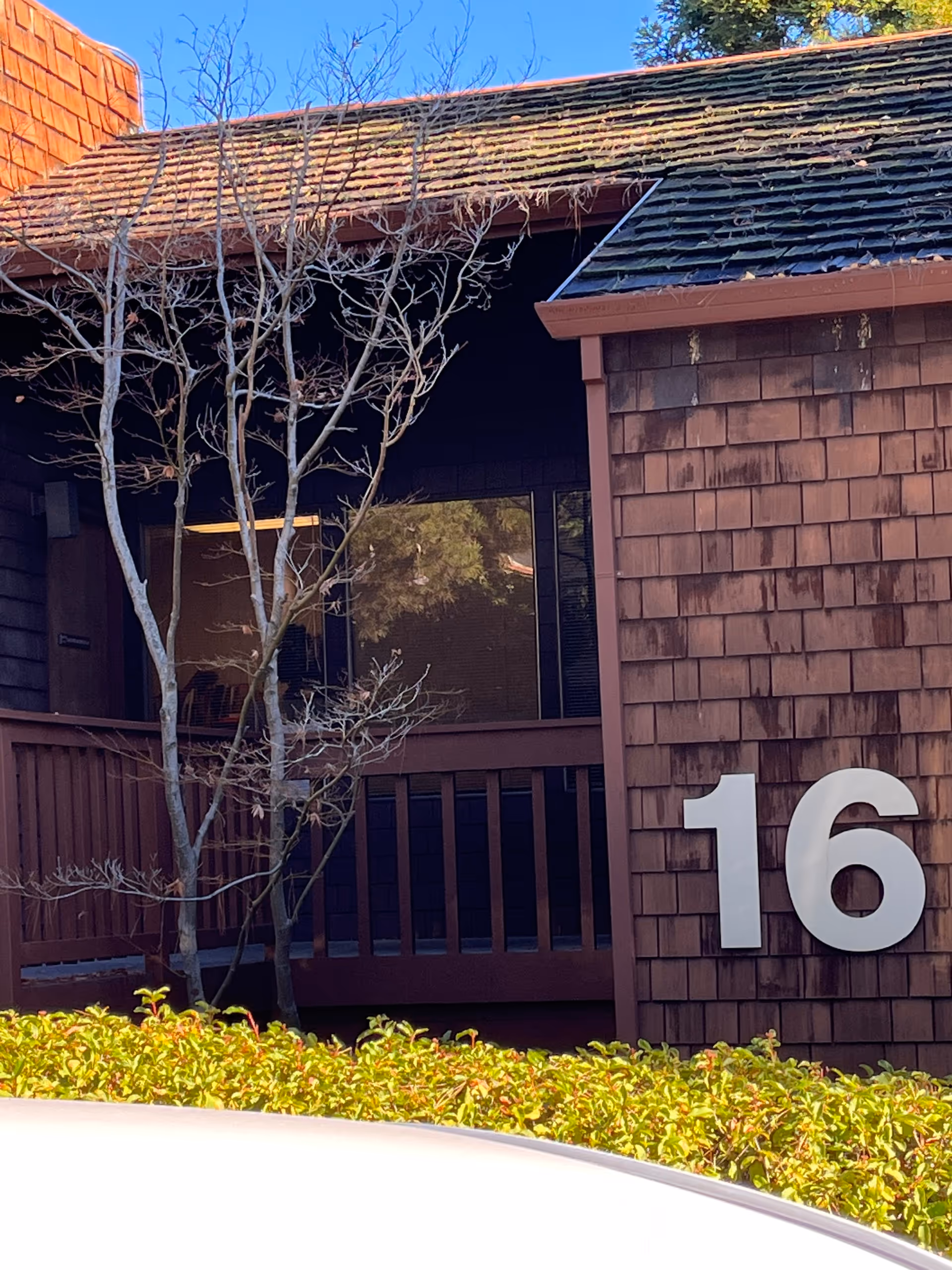Exterior view of a brown wooden senior living building with the number 16 and trees.