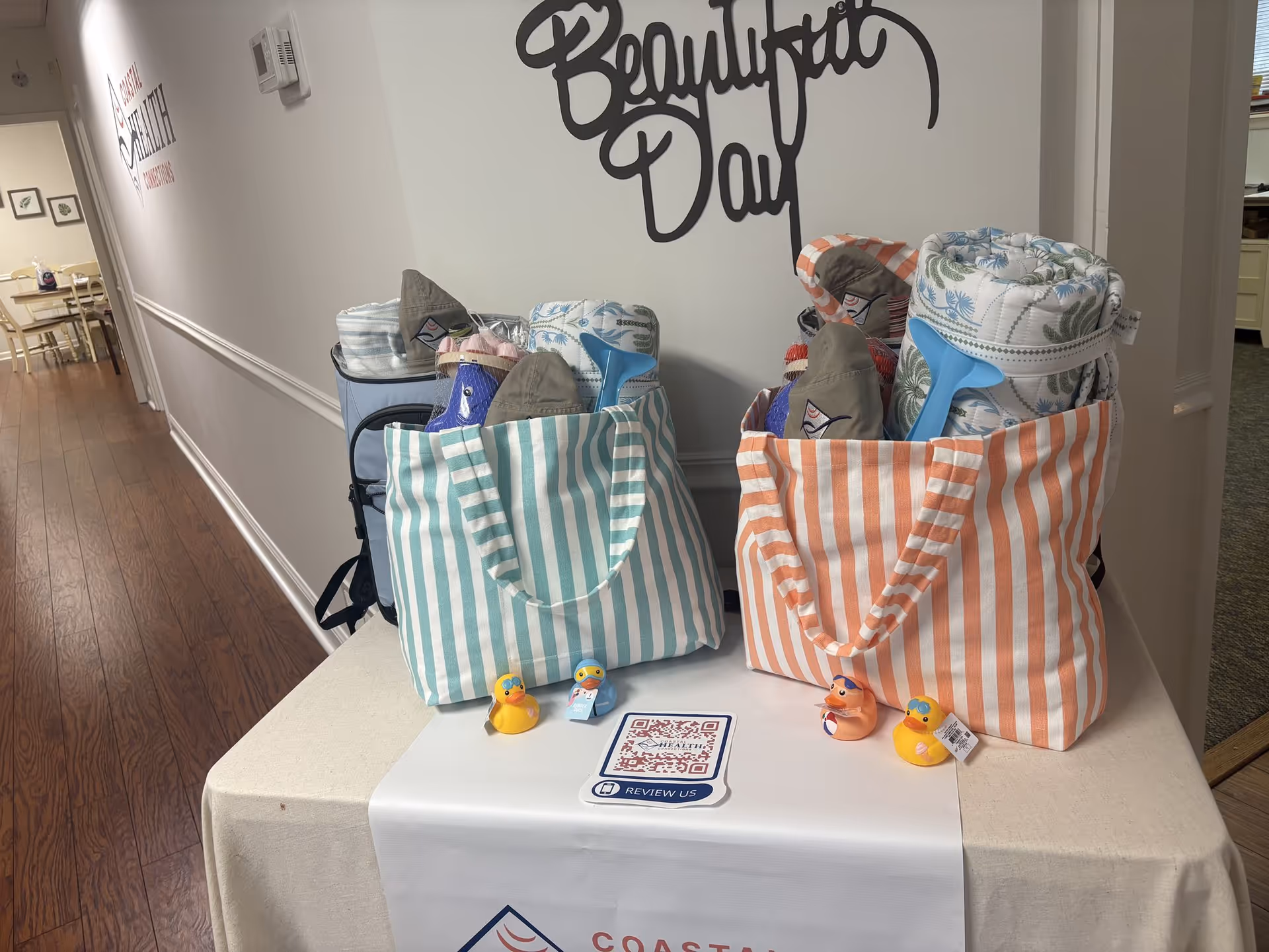 Two striped tote bags with blankets and rubber ducks sit on a table in a hallway.
