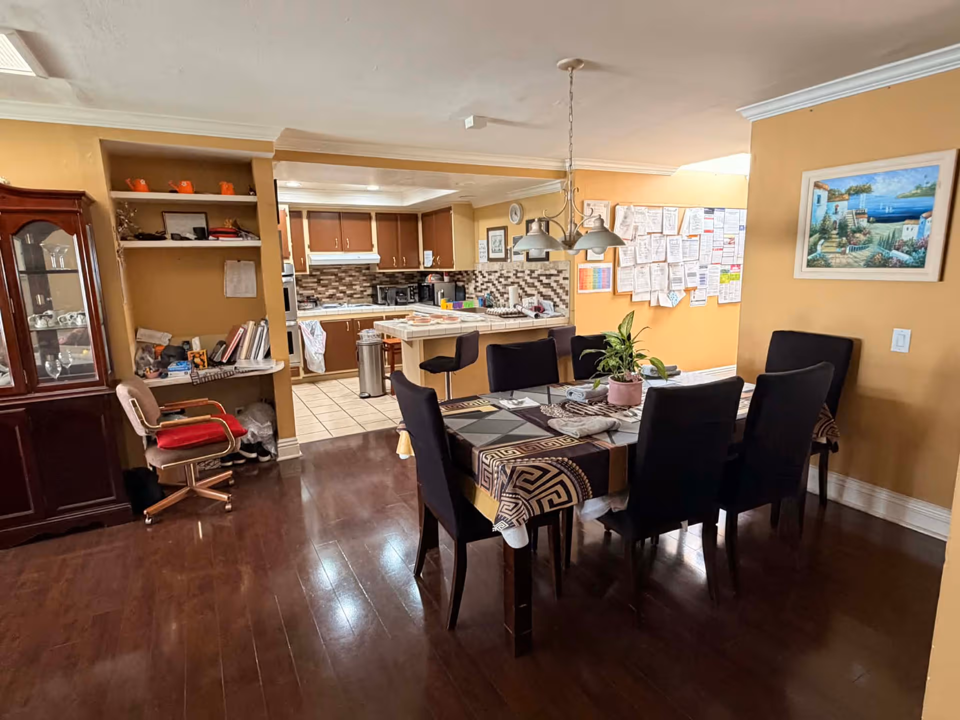 Communal dining area with a dark wood table and kitchen in the background.