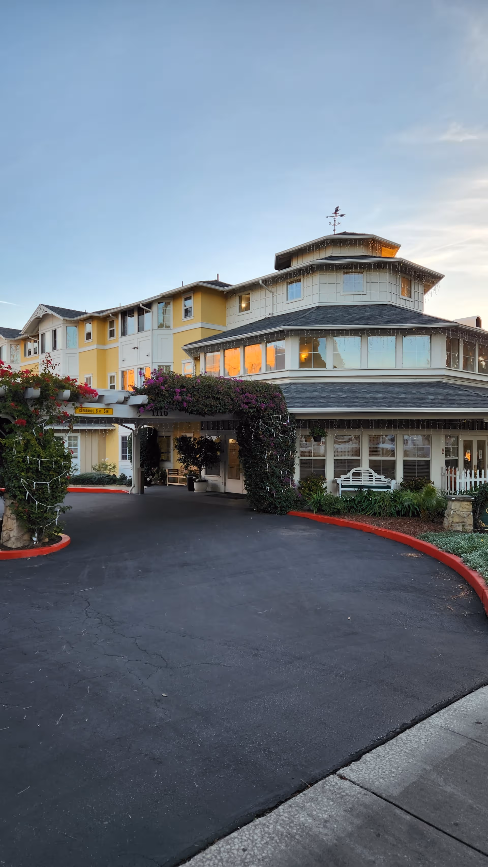 Exterior view of a Garden Court senior living facility with a curved entrance and landscaped front.
