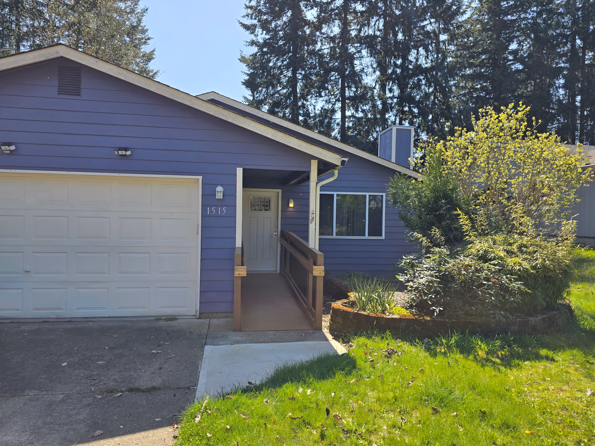 Purple single-story house with ramped front entrance, attached garage, and landscaped yard.