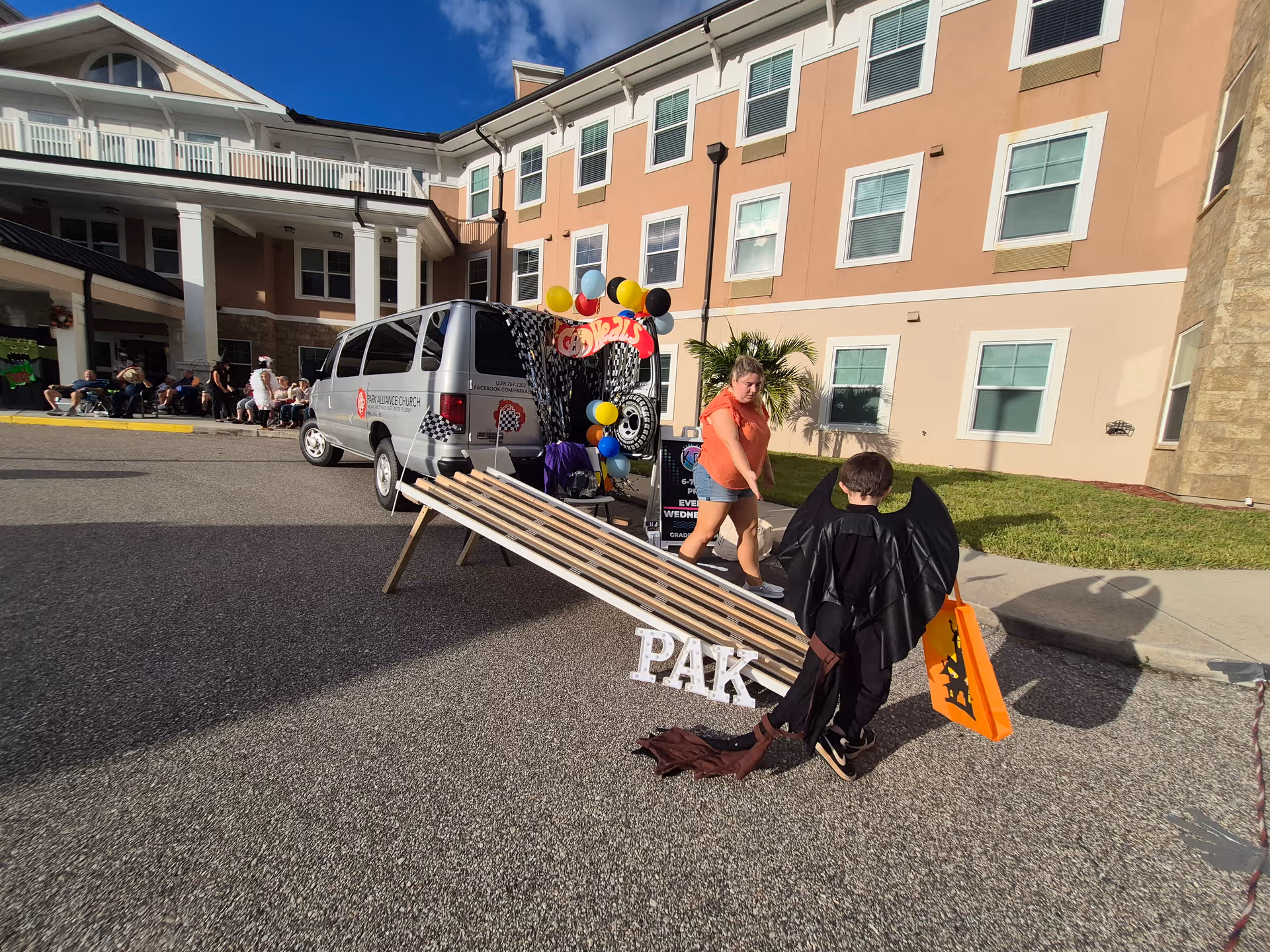 Canterfield Senior Living exterior with a van, ramp display, balloons, and costumed figure.