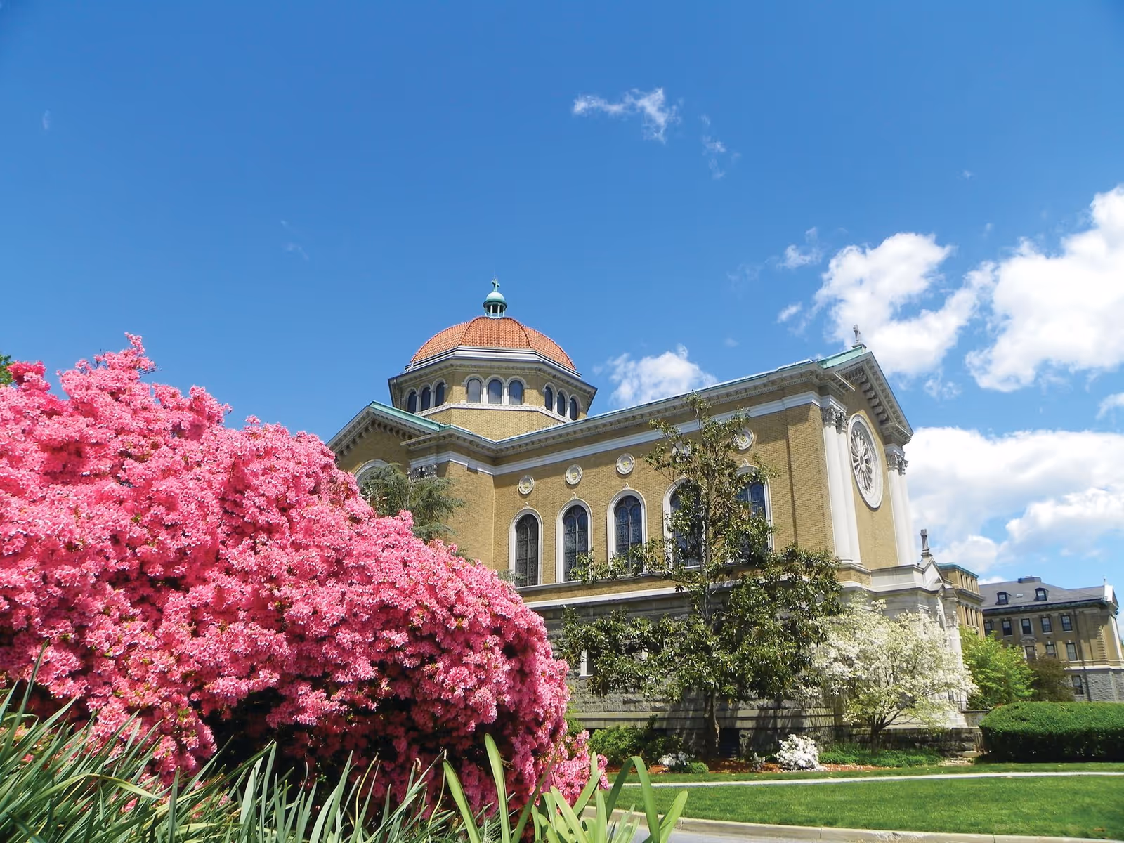 Charlestown facility exterior with brick building, dome, pink flowering bushes, and blue sky.