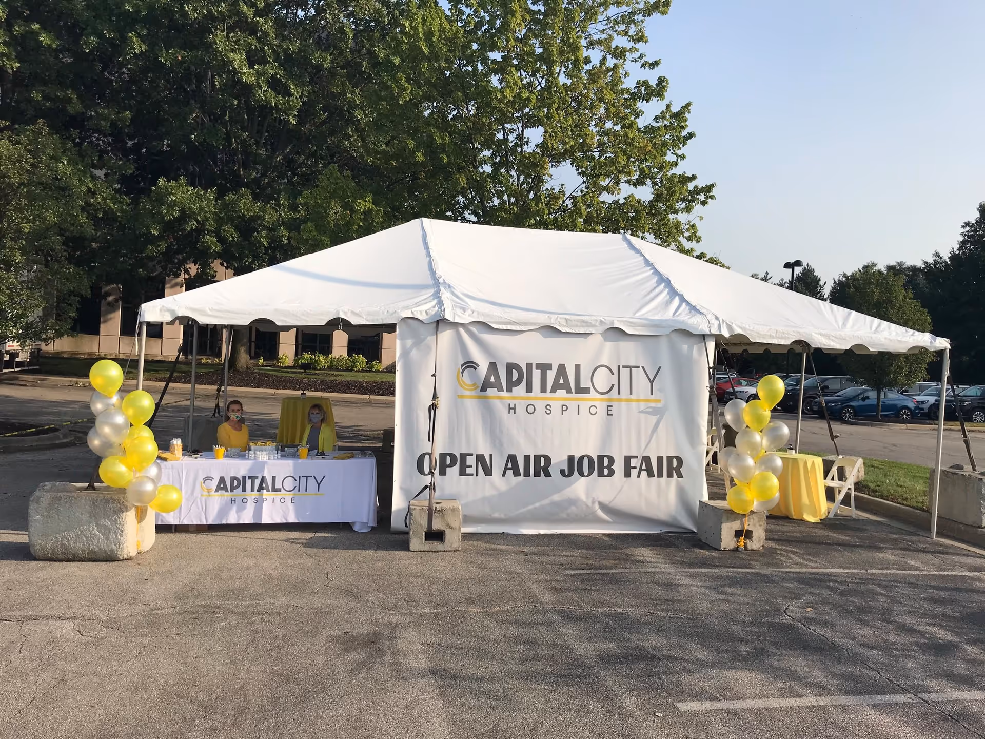 Outdoor Capital City Hospice tent hosting an open air job fair with staff at a table.