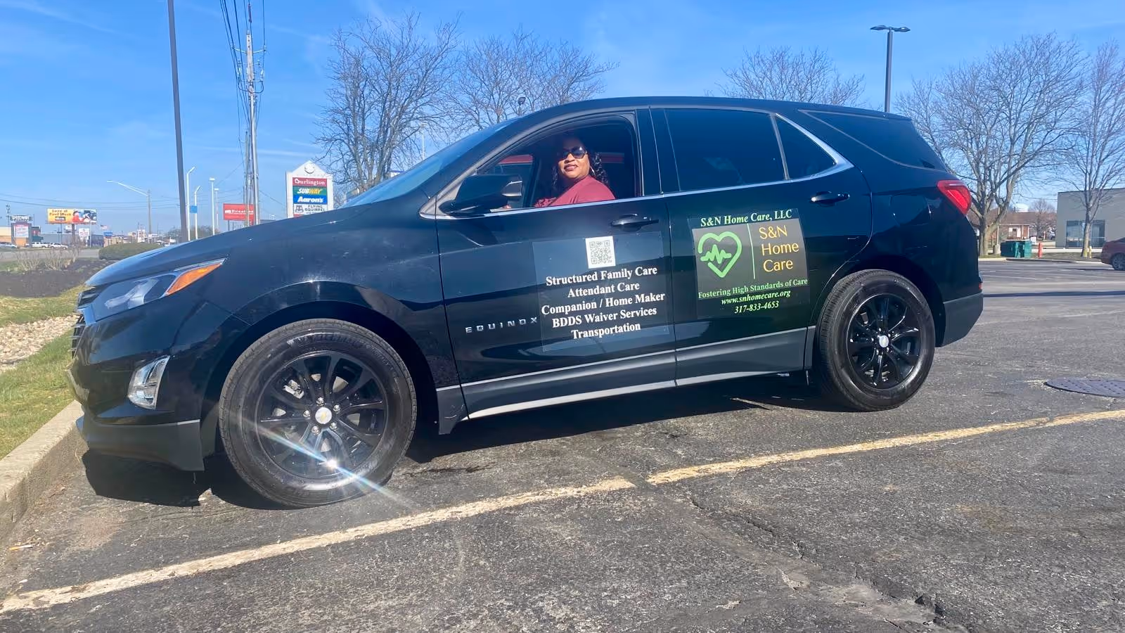 Branded black SUV in a parking lot with a driver inside, displaying S&N Home Care logos.