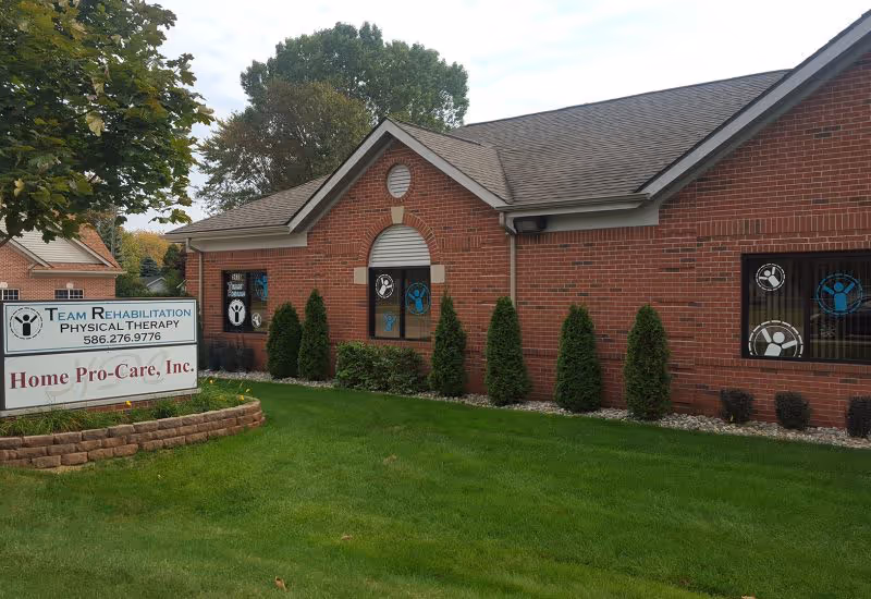 Exterior view of a brick rehab facility with a manicured lawn and sign.
