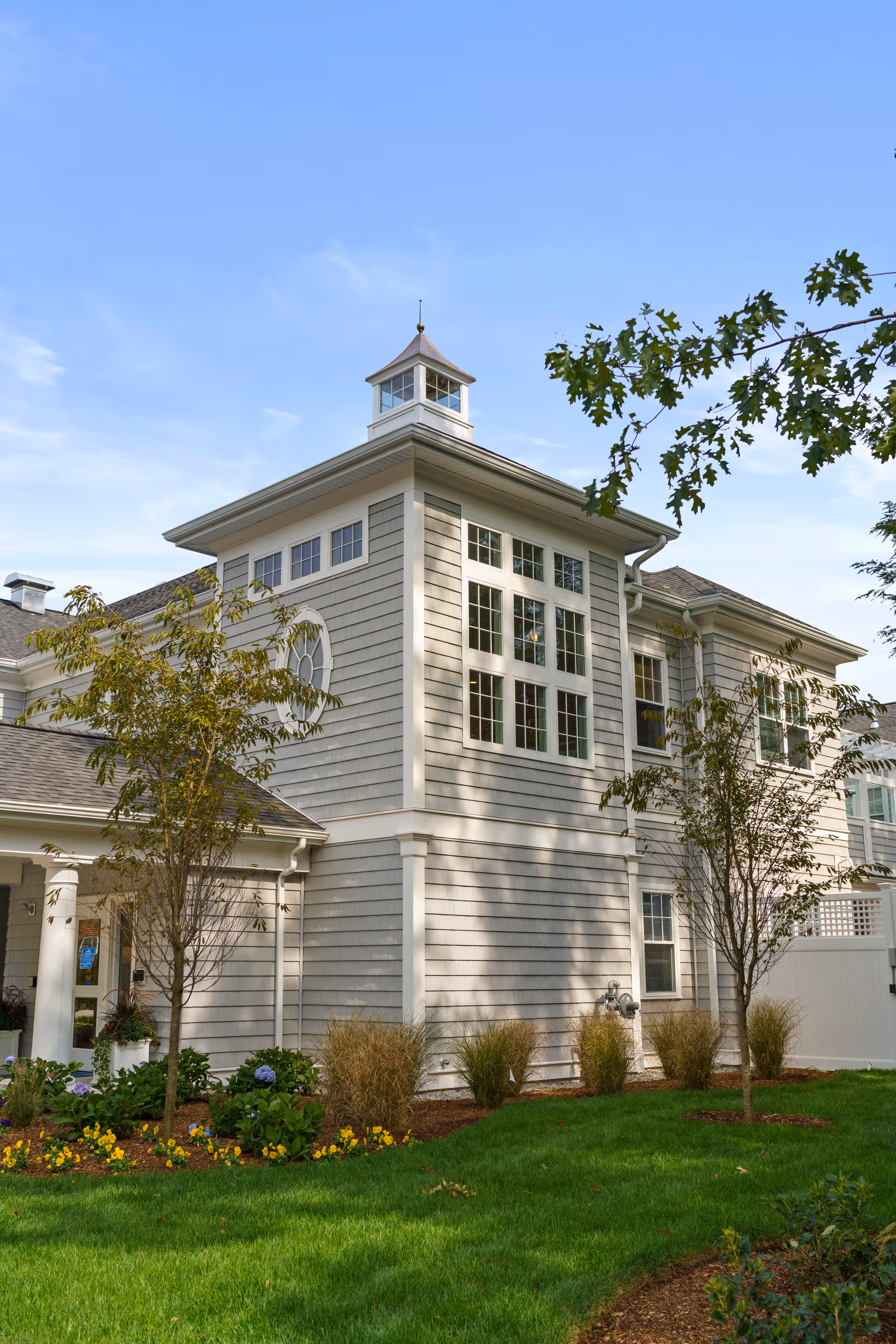 Exterior view of a light-gray senior living facility with windows and landscaping.