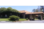 Braswell's Mediterranean Gardens exterior with a tiled roof entrance and manicured hedges.