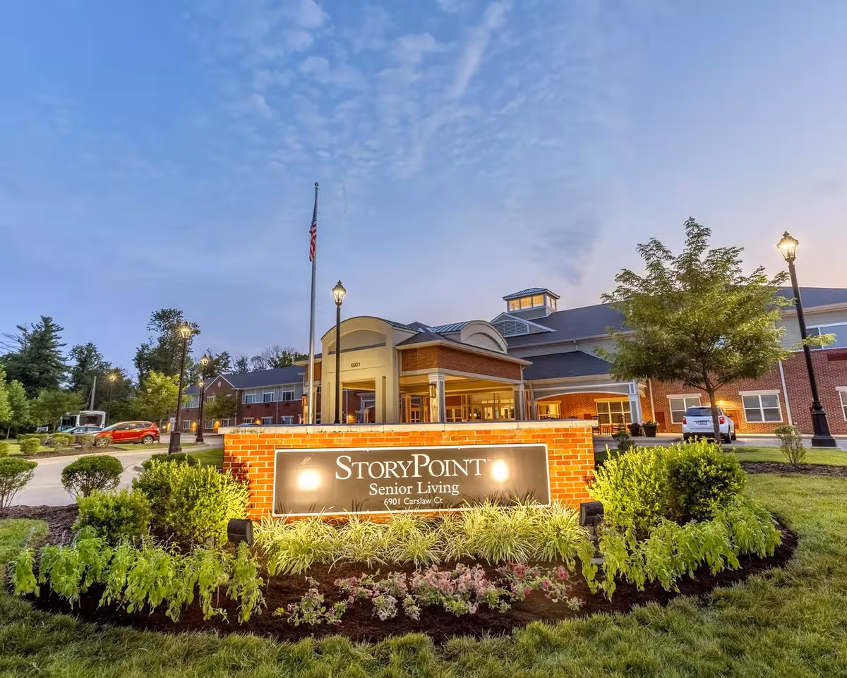 Front exterior of StoryPoint Prospect Senior Living with illuminated sign and landscaped entry.